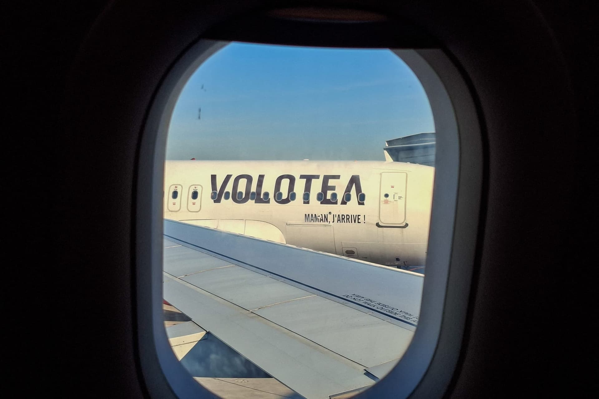 Vue depuis le hublot d'un avion, un appareil Volotea est stationné sur le tarmac, son fuselage parfaitement visible et son slogan inscrit en grandes lettres à l'aéroport de Paris-Orly, le 22 avril 2026.